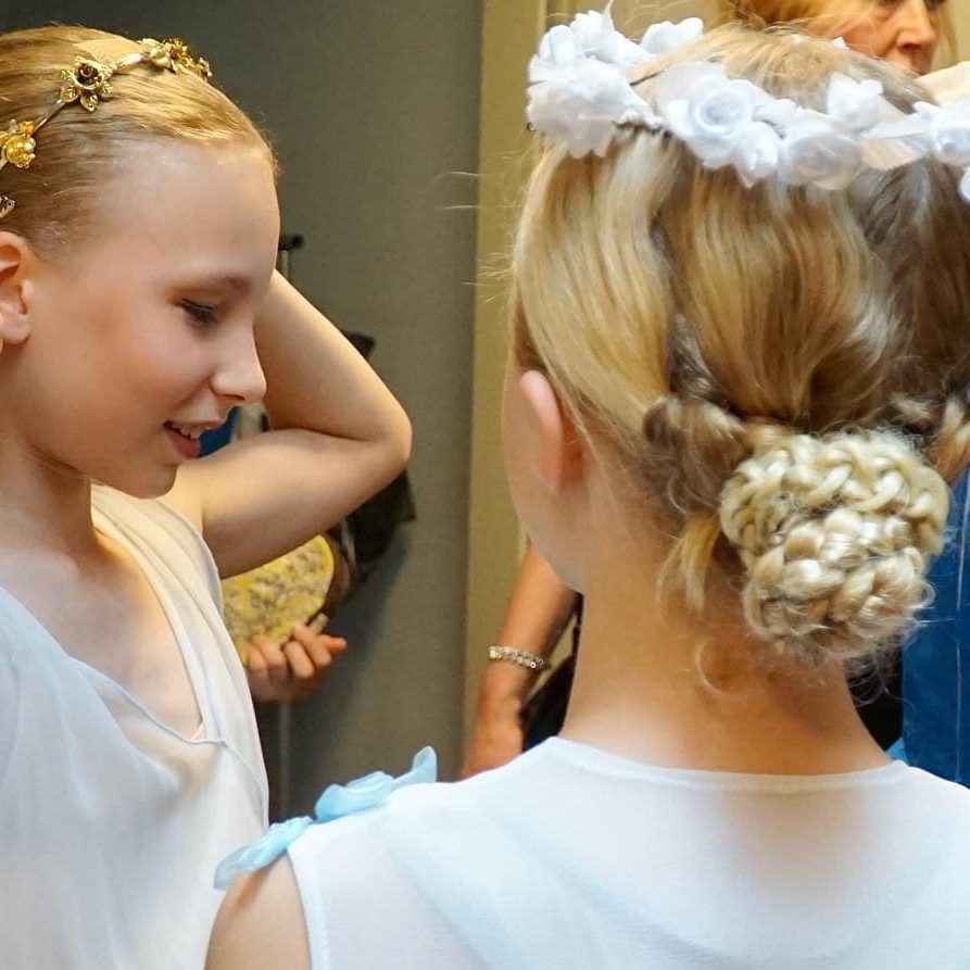 Backstage Foto: Maria Tkalina Ein Mädchen steht mit dem Rücken begutachtet sich in Ihrem blauen Kostüm und zupft an Ihrem Blumenkranz auf dem Kopf.