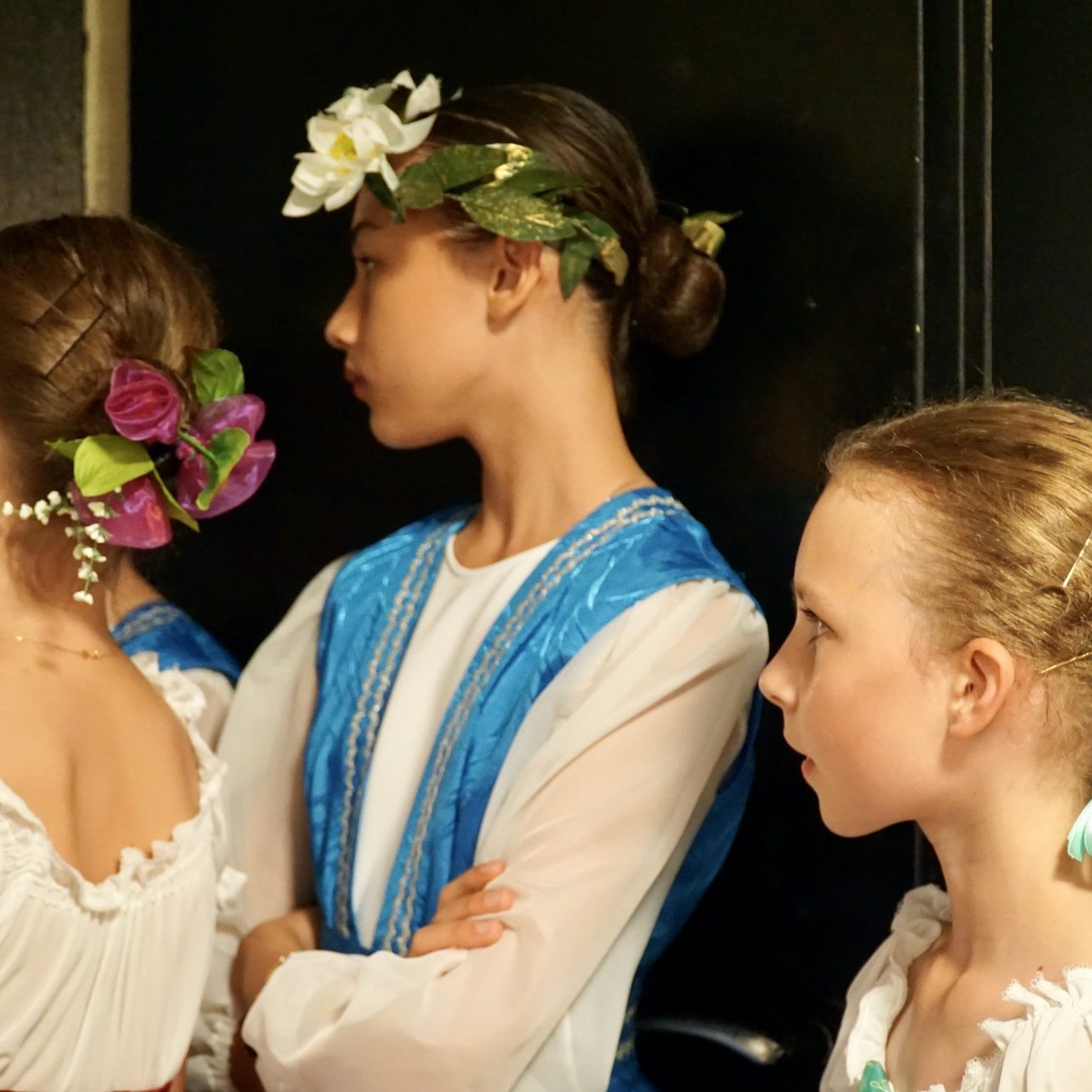 Vor der Vorstellung/Foto: Maria Tkalina 3 Kinder warten im Kostüm vor dem Auftritt im Backstage und wirken konzentriert.